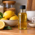 a bottle of lemon extract on a kitchen counter next to a bowl of lemons