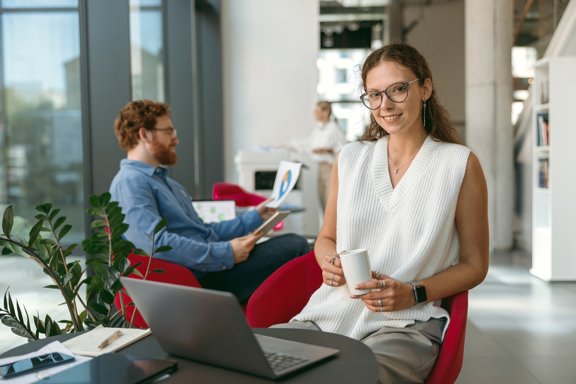 Female sales manager working on laptop and drink coffee sitting in modern coworking and looks
